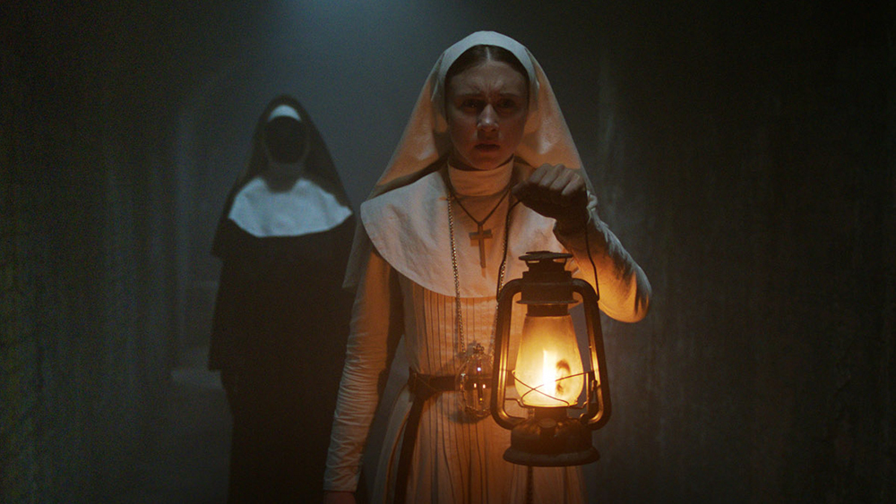 taissa farmiga dressed as a nun holding a lanter
